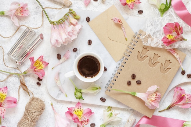 Café e açúcar em uma mesa branca entre a vista superior de flores rosa