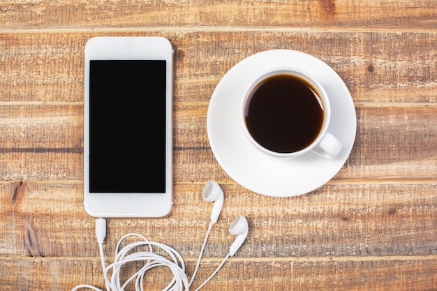 Café e celular com fones de ouvido