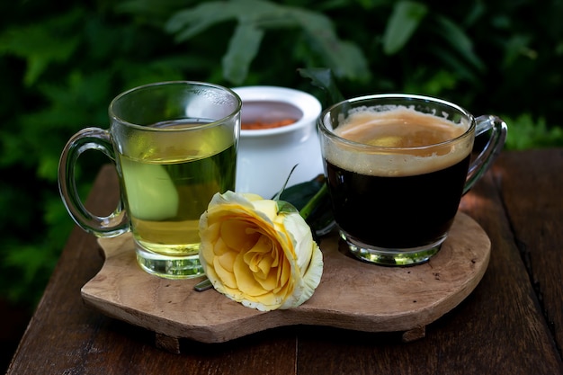 Café e chá estão sobre a mesa de madeira no jardim verde