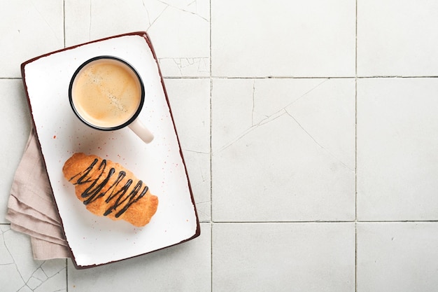 Café e croissant Café expresso e croissant com chocolate na velha mesa de ladrilhos rachados Croissant perfeito Café da manhã estilo rústico Vista superior Mock up