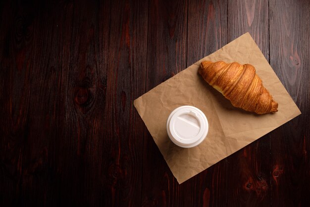 Café e croissant na mesa de madeira