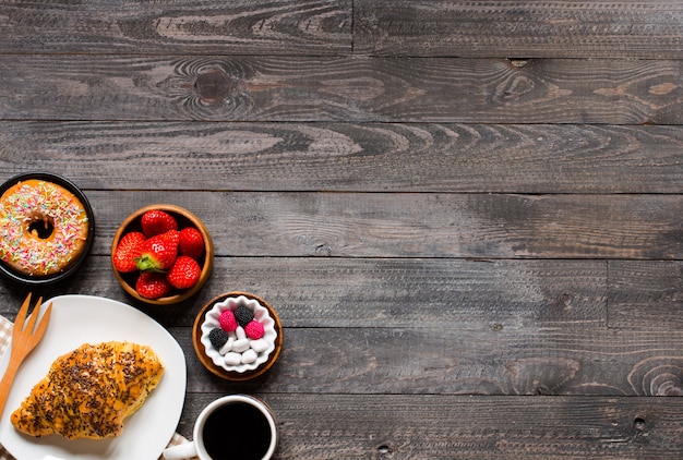 Café e croissant no café da manhã em fundo de madeira rústico