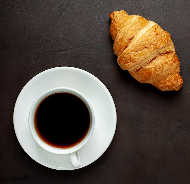 Café e croissants na tábua de madeira