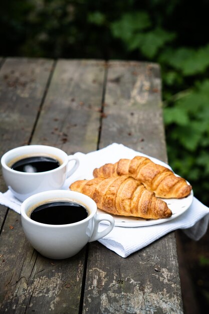 Café e croissants na velha mesa de madeira rústica