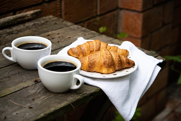 Café e croissants na velha mesa de madeira rústica