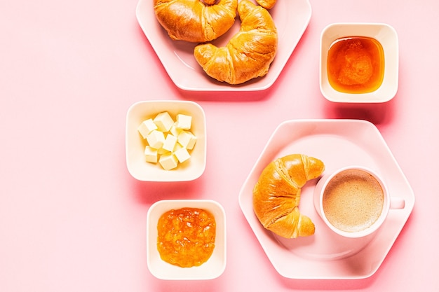 Café e croissants no café da manhã em um fundo rosa