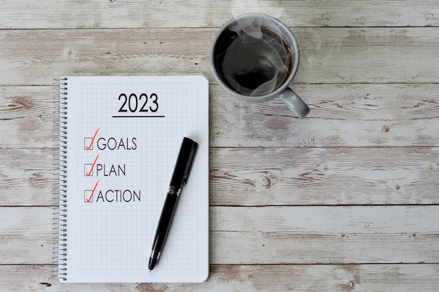 Café e notebook com uma lista de tarefas para os objetivos do conceito do ano 2023 e plano de ação para o ano novo
