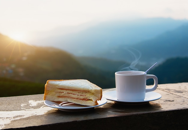 Foto café e sanduíche de manhã na vista para a montanha.