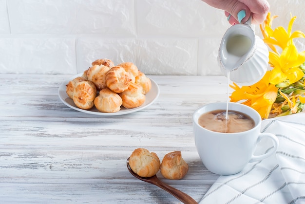 Café y eclairs sobre una mesa blanca.