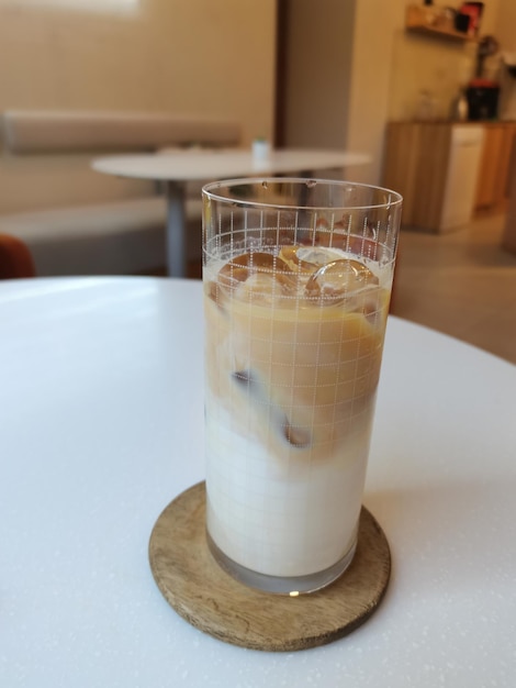 Foto café em copo com café com gelo em cores claras em uma mesa branca lugar de café elegante para