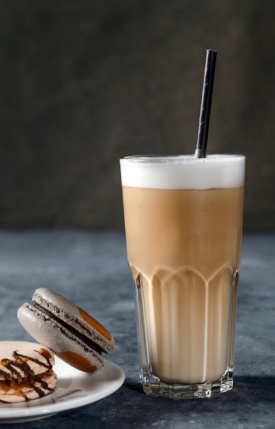 Café em copo com creme derramado e macaron em uma velha mesa rústica cinza