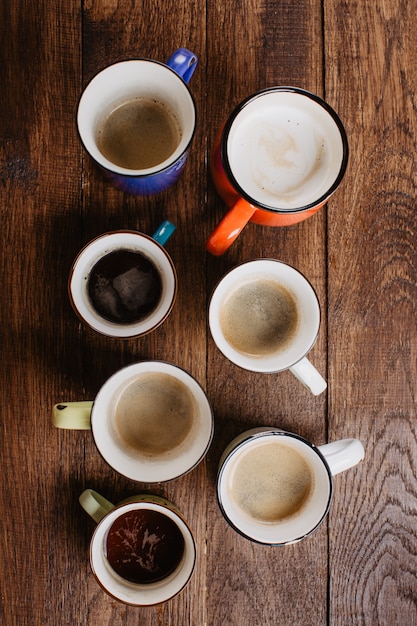 café em copos diferentes em um fundo de madeira