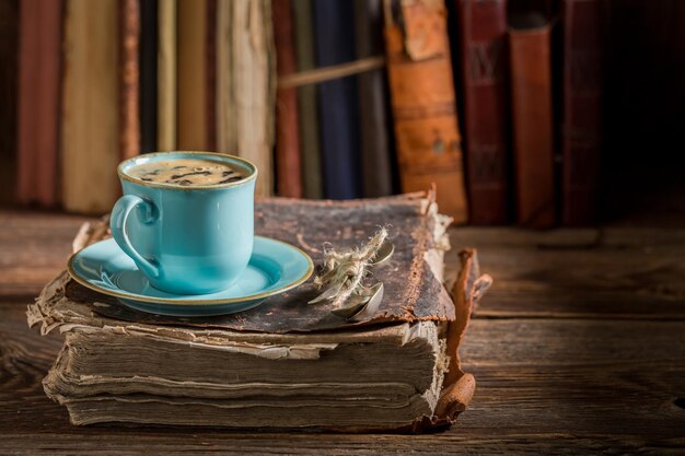 Café em porcelana azul na biblioteca no livro antigo