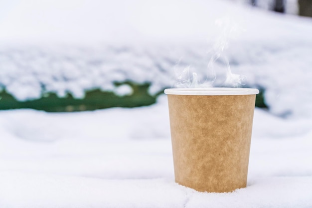 Foto café em um copo de papel em um fundo de inverno com neve bebida quente em clima frio foto de alta qualidade