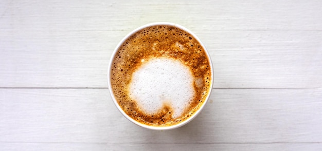 Café em um copo descartável em uma vista superior de fundo branco de madeira