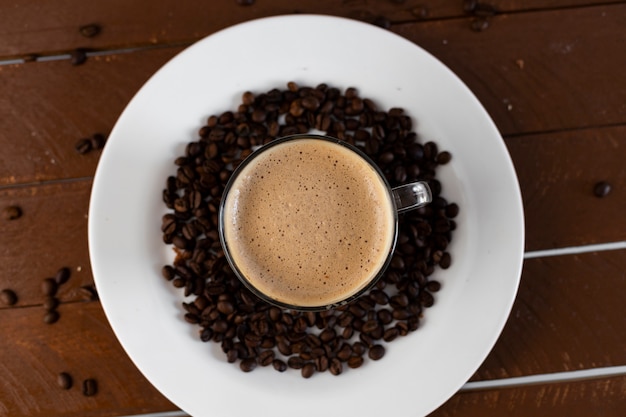 Café em um prato branco com grãos ao redor