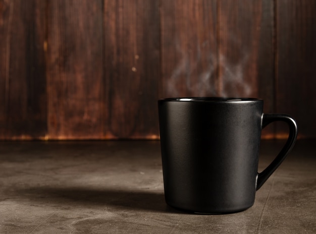 Foto café em uma caneca preta com fundo escuro de madeira