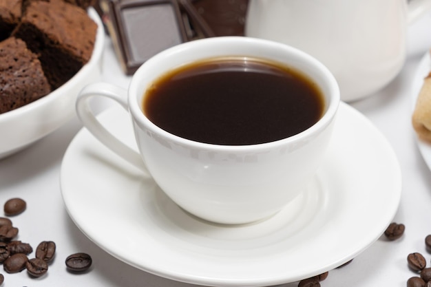 Café em uma xícara de bolo de chocolate e pedaços de chocolate em um fundo branco