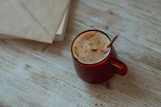 Café em uma xícara de vidro e correio matinal em uma mesa de madeira