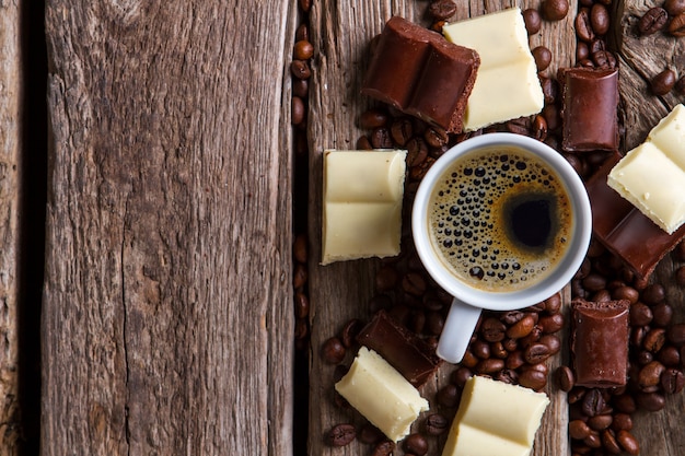 Café em xícara branca. Chocolate ao lado de grãos de café. Bebida quente com sabor amargo. Tome uma xícara de café expresso.