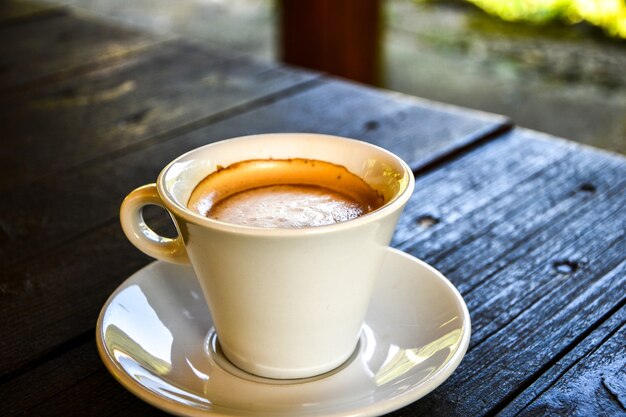 Café em xícara branca na mesa de madeira escura na cafeteria. Cafeteria