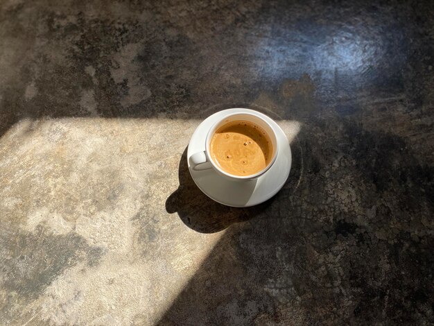 Foto café em xícara branca no chão de cimento com fundo de iluminação