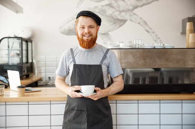 Café Empresario Concepto - Retrato de joven feliz barbudo caucásicos barista en delantal con confianza buscando servicio de café caliente al cliente en mostrador de cafetería.