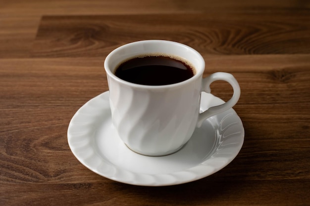 Café escuro em caneca branca na mesa de madeiraxDxA