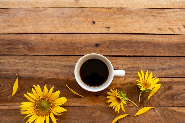 café espresso caliente con arreglo de girasoles de flores en madera