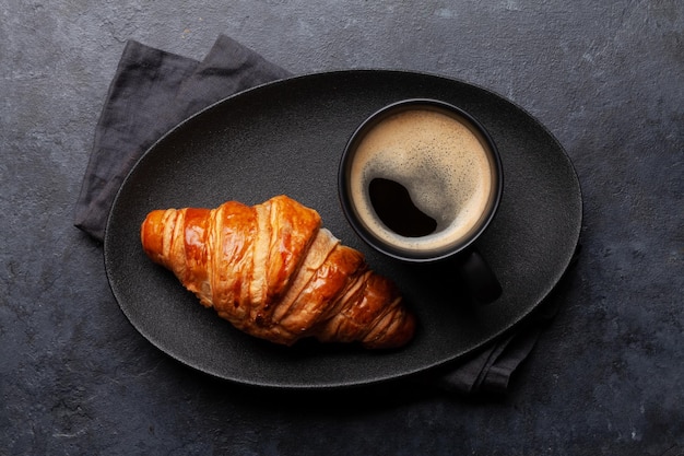 Café espresso y croissant para el desayuno.