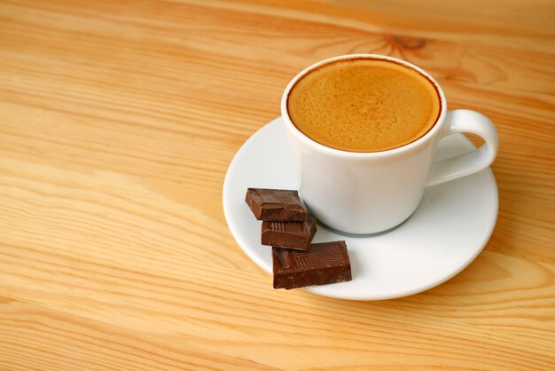 Café espresso y cubos de chocolate oscuro servidos en una mesa de madera