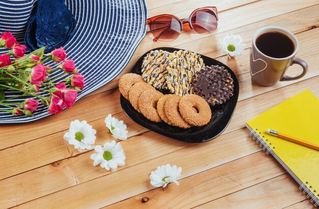 Café espresso se encuentra en una mesa de madera con galletas, bloc y lápiz.