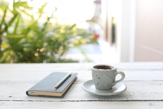 Café espresso en una taza con libreta y lápiz.