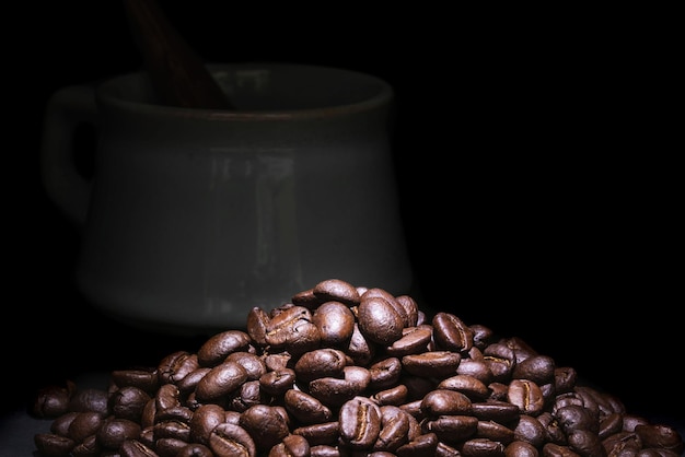 Café espresso en la vieja taza de cristal y granos de café en el suelo, tono oscuro, primer plano