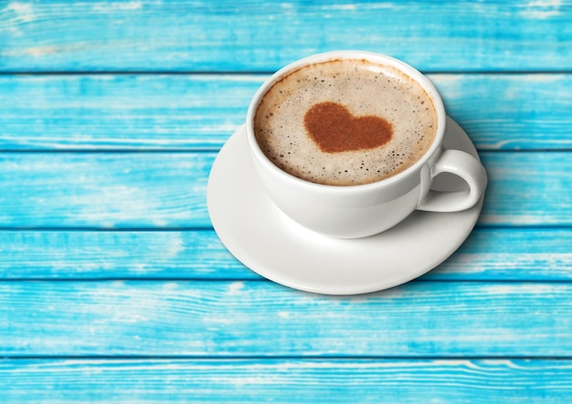 Café con espuma en forma de corazón sobre fondo de madera