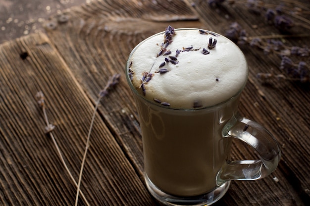 Café con espuma de leche en taza transparente con ramitas de lavanda.