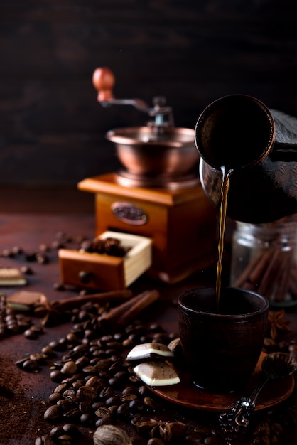 Café está derramando para a taça no fundo de pedra escura com grãos de café