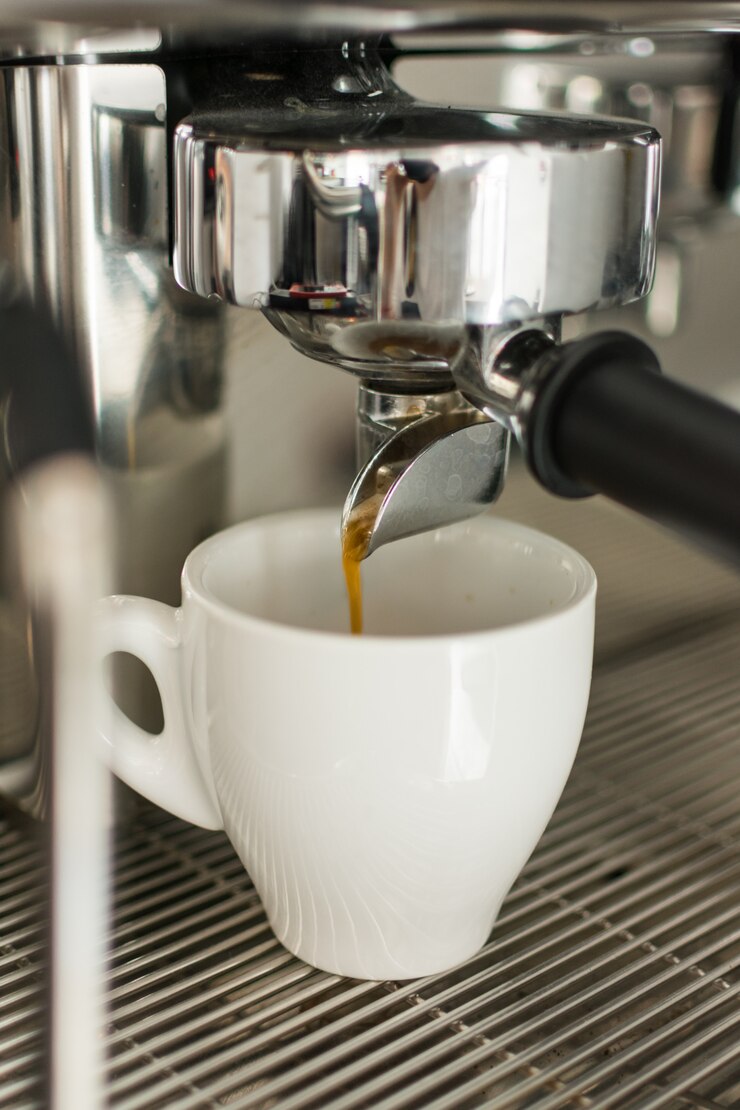 Café expreso que vierte de la máquina de café en una taza
