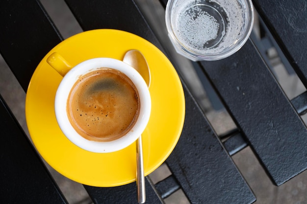 Foto café expreso en taza amarilla con un vaso de agua con gas en la vista superior de la cafetería