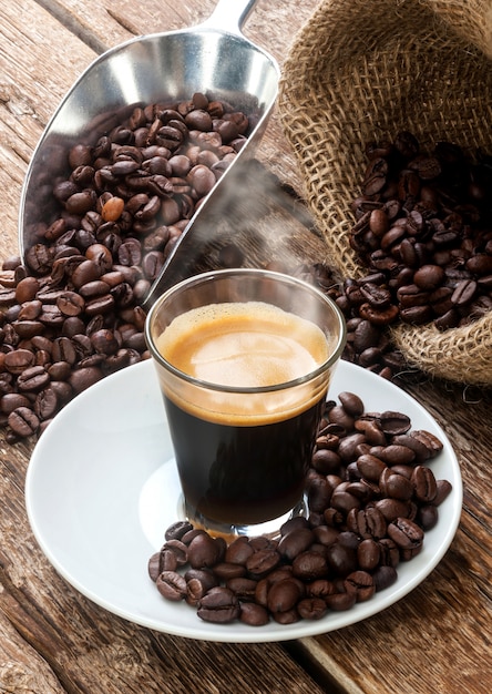 Café expreso en taza de cristal con granos de café.