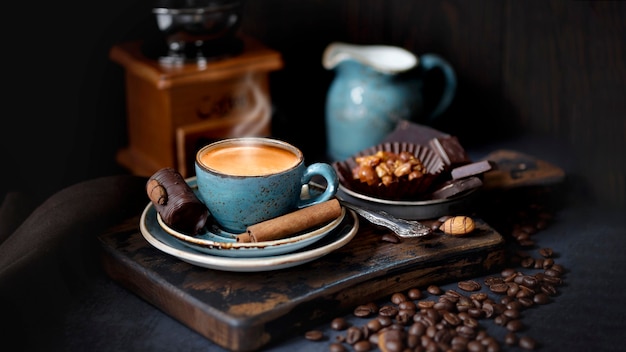 Café expresso com canela em pau. Xícara de café azul em uma placa de madeira, grãos de café