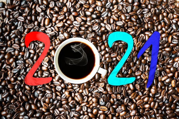 Café expresso com número 2021 sobre grãos de café