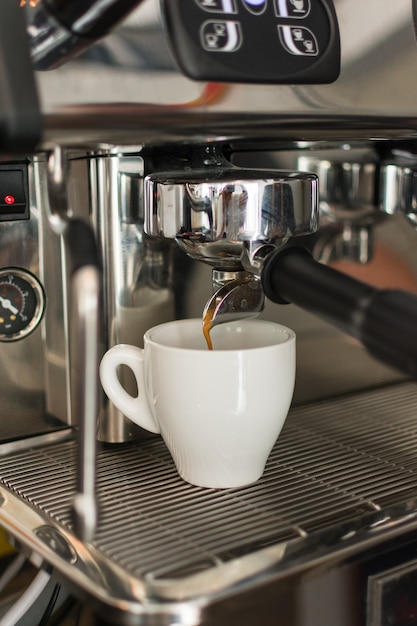 Café expresso derramando da máquina de café em um copo