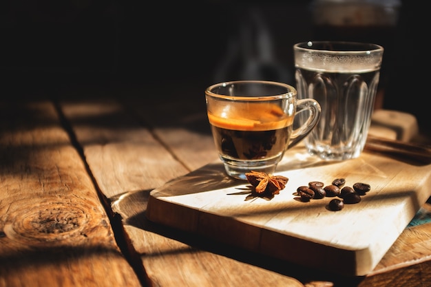 Café expresso e água fria em uma velha mesa de madeira.