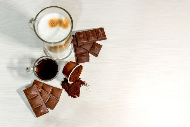 Café expresso em fundo branco com cápsula aberta e chocolate.