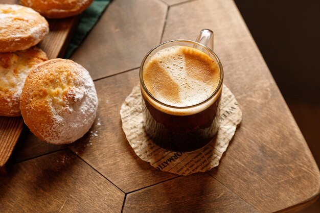 Café expresso em uma caneca de vidro com cheesecake em um fundo de madeira