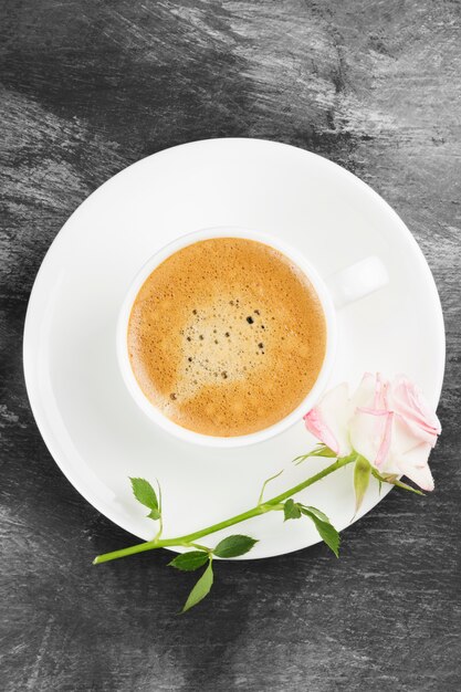 Café expresso em uma xícara branca, uma rosa cor de rosa e chocolates em um fundo escuro. Vista do topo. Fundo de alimentos.