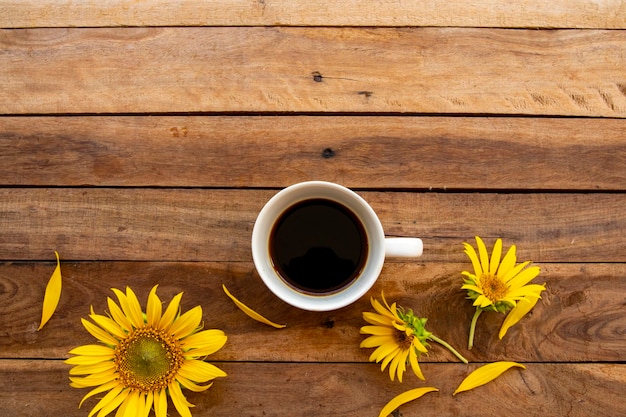 café expresso quente com arranjo de girassóis de flores em madeira