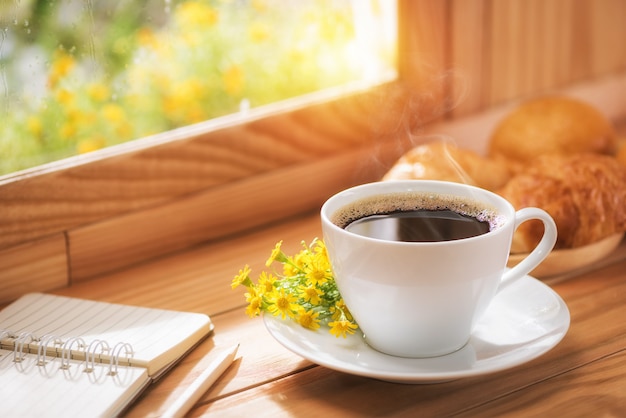 Café y flores para el desayuno junto a la ventana con la luz del sol de la mañana