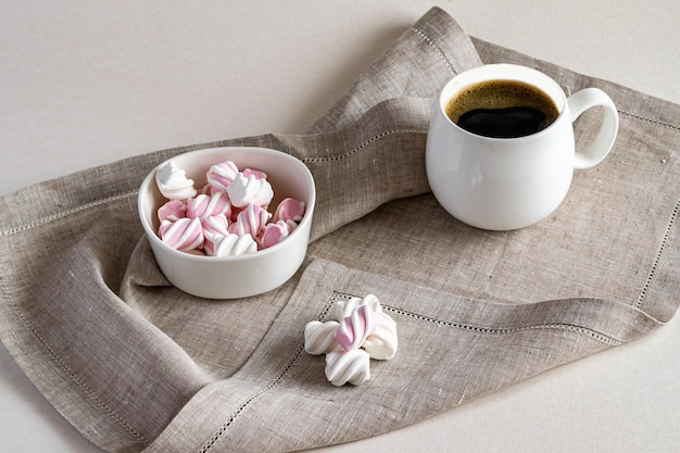 Café fragante caliente y malvavisco dulce en un tazón blanco sobre una servilleta de lino Foto horizontal